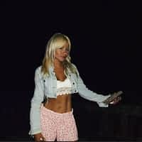 Lisa Gali pornstar posing with white croptop and pink pants, at the beach.