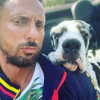 Andrew Milan pornstar in a car with a dog resting his head on his shoulder.