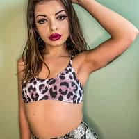 Mary Jane porn actress posing in leopard print crop top and skirt, with one of her hands rouching her hair.