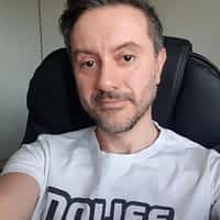 Rico Simmons porn actor on blakc desk chair, wearing white "no life" shirt, taking a selfie.