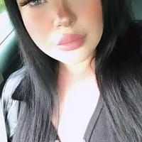Anastasia XXX pornstar sitting in a car and taking a selfie while pouting her lips.