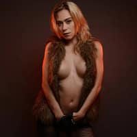 Anouk Maze naked wearing only a fluffy vest, posing while covering her vagina with her hands.