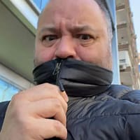 Torbe porn actor in north face coat hiding his mouth behind the collar and making a surprised face.