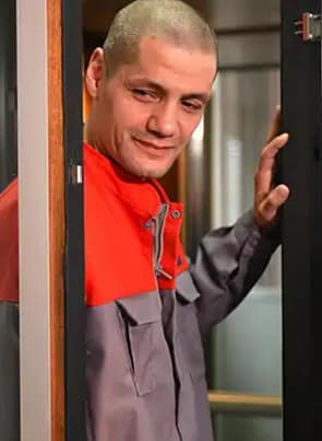 Olivier Lecoeur pornstar posing against a door in red and grey jacket.